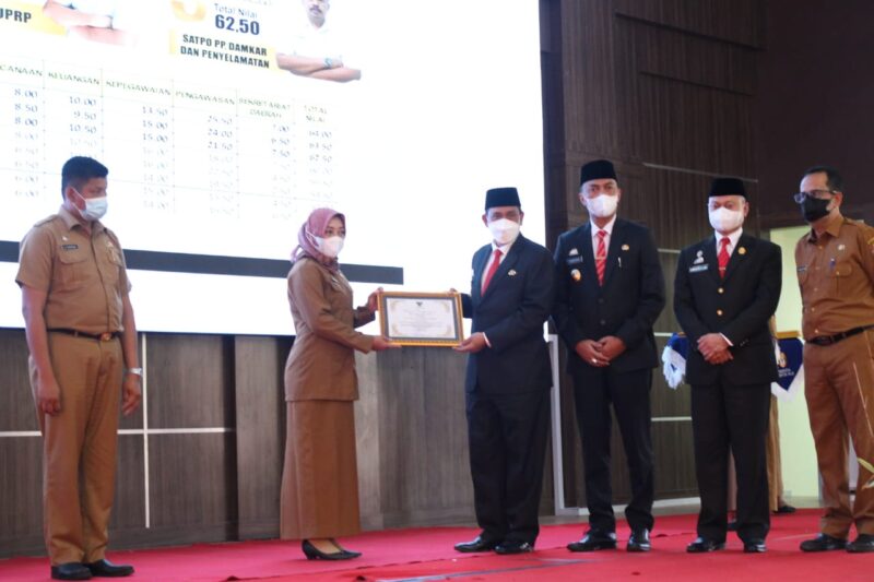 Bupati Wajo H. Amran Mahmud didampingi Wakil Bupati Wajo H. Amran SE, Ketua DPRD Wajo H.A Alauddin Palaguna dan Plt Sekda Wajo menyerahkan penghargaan kepada Kepala Dinas Kesehatan Dr. Hj. Armin kategori Pelaksana Urusan Pemerintahan Wajib Pelayanan Dasar