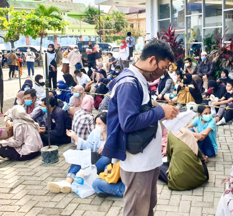 Warga masyarakat rela antri di bawah sengatan matahari demi untuk mendapatkan vaksin gratis