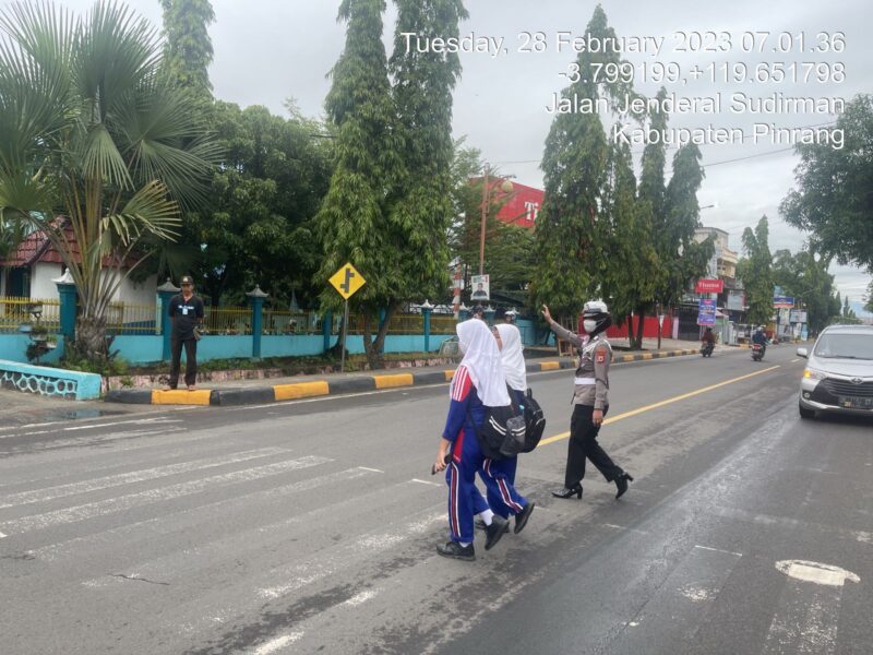 Personil polres pinrang menyeberangkan siswi SMPN 1 Pinrang