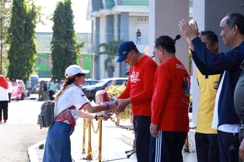Peserta Devile yang tergabung dalam barisan UMKM Diskop, Mila dari KP. Exotico menyerahkan Minuman segar unggulannya kepada Bupati Pinrang di saksikan Wabup Pinrang