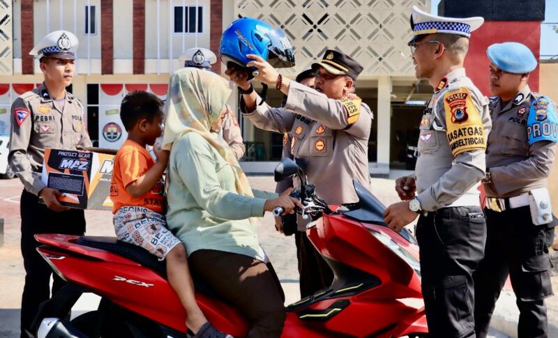 Kapolres Barru AKBP Dodik Susianto, S.I.K  memasangkan helm standar ke pengendara roda dua