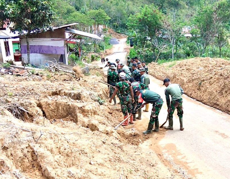 Personel Koramil 01/LT bersama Satgas YTP 854 bergotong royong membersihkan material tanah longsor yang menutup badan jalan di Desa One-One.